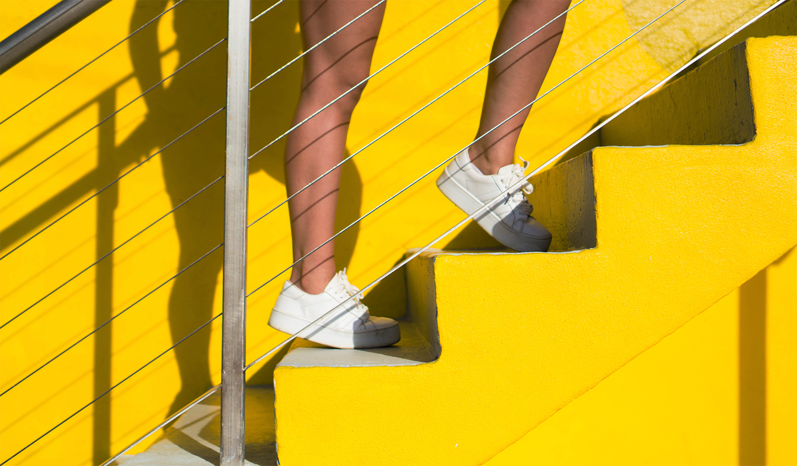 women climbing yellow steps in white trainers