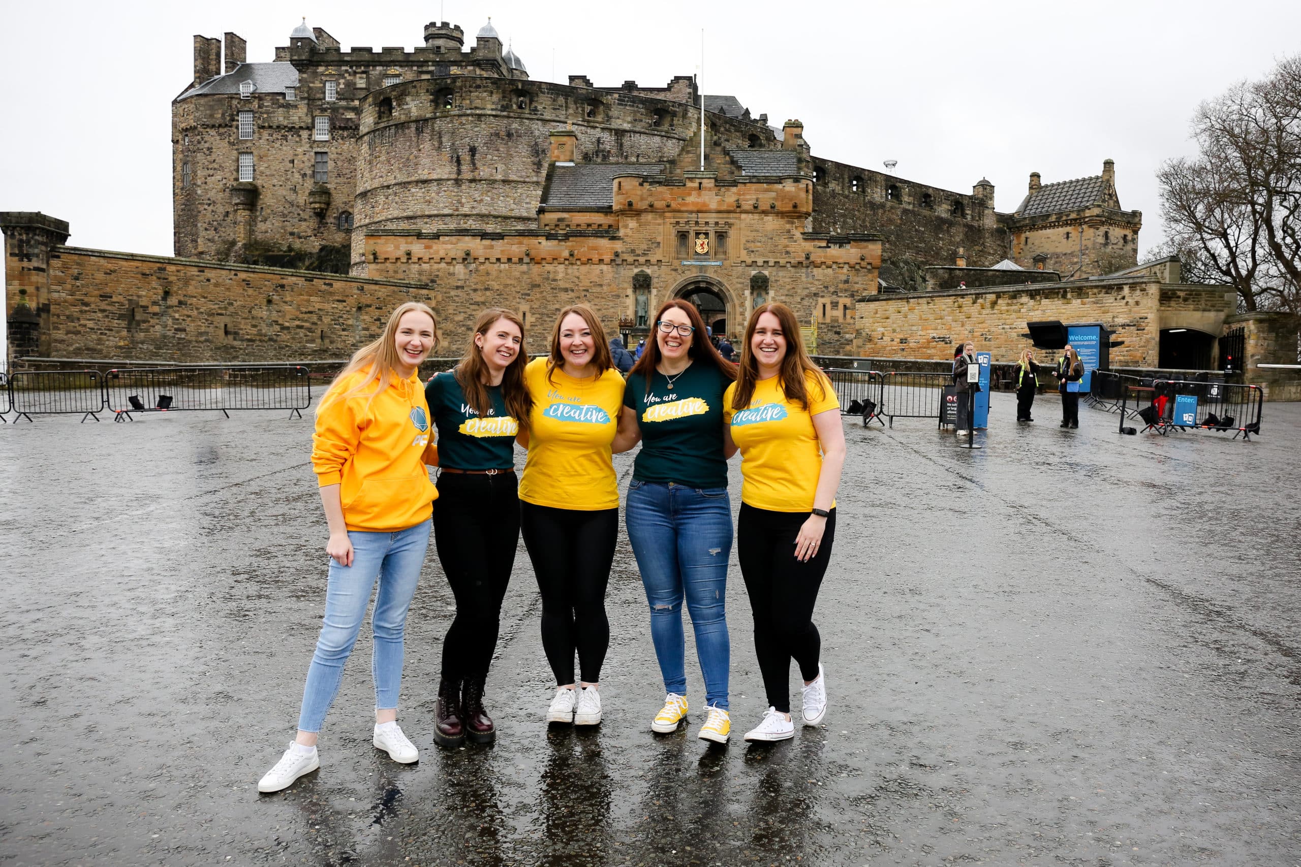 people in yellow and green t-shirts in front of Edinburgh castle