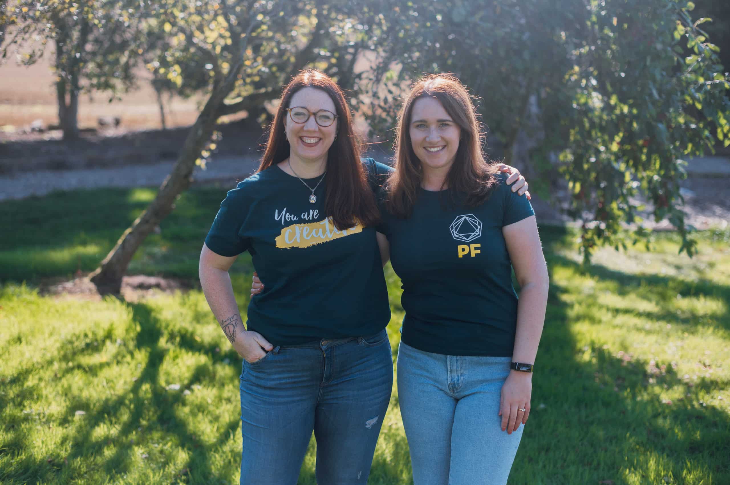 Two women standing in green t-shirts outside in the sun - successful marketing manager